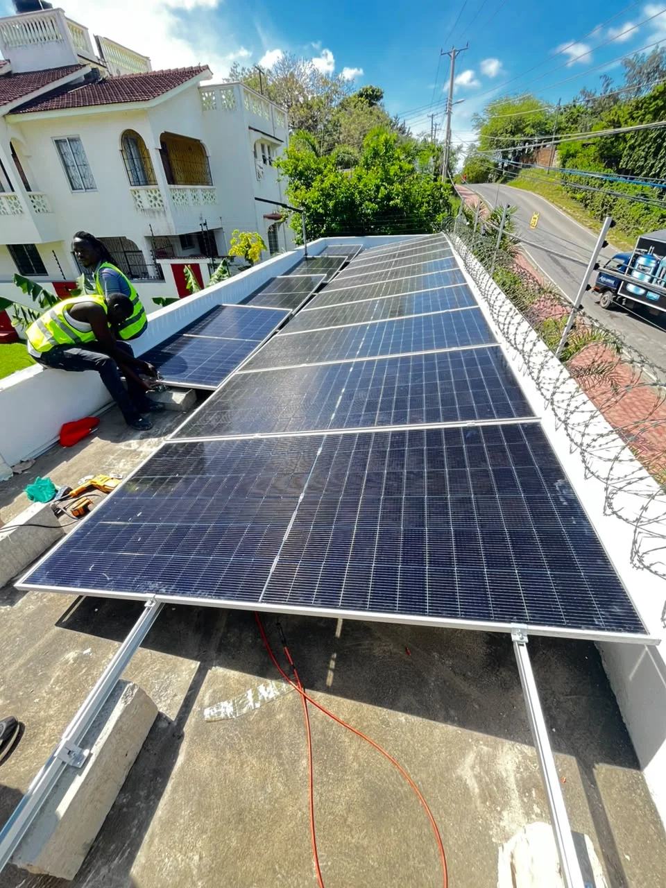 PCLEINE technicians mounting monocrystalline solar modules on ballast mounts in Milimani Estate, Nyali