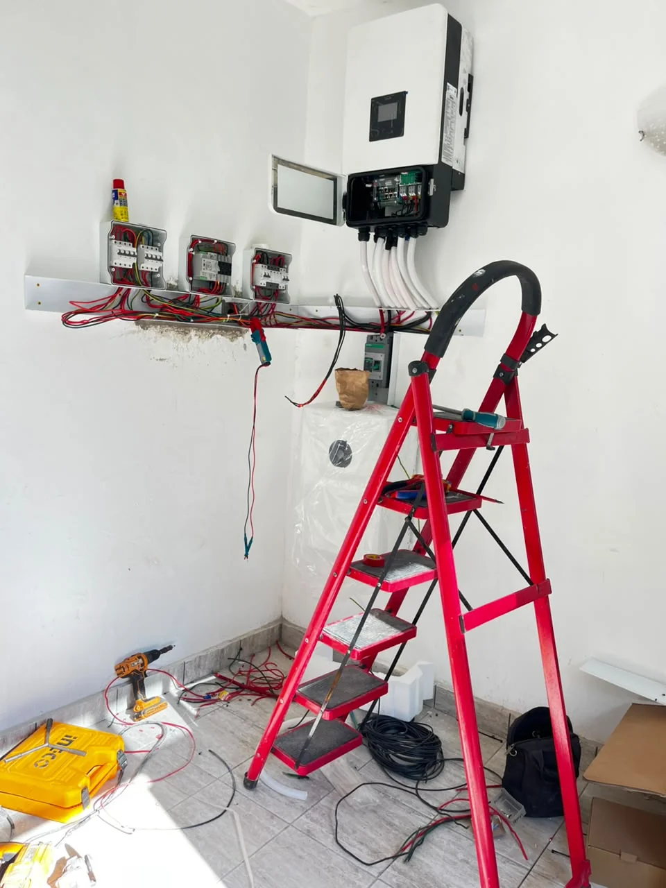PCLEINE technicians mounting Deye hybrid inverter, routing conduits and wiring switchgear during installation in Nyali